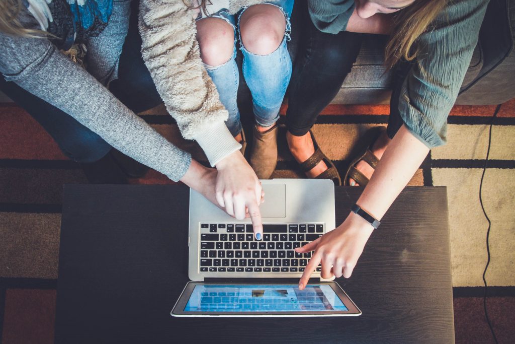 People pointing finger on laptop while looking at something on it