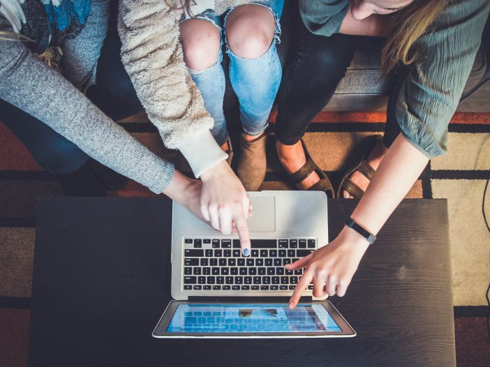 People pointing finger on laptop while looking at something on it